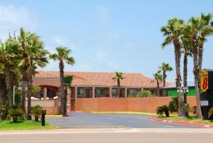 a building with palm trees in front of a street at Super 8 by Wyndham South Padre Island in South Padre Island