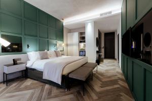a bedroom with a large bed and a green wall at The Embassy Valletta Hotel in Valletta