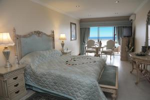 una camera con un grande letto e vista sull'oceano di Misty Waves Boutique Hotel a Hermanus