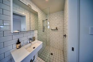 a white tiled bathroom with a sink and a mirror at The Signature Lofts in Morpeth +17 photos