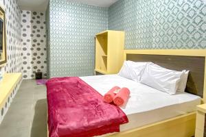 una camera da letto con un letto con due asciugamani rosa di Tini's Guest House Malang Mitra RedDoorz a Betek