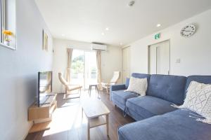 sala de estar con sofá azul y sillas en villa PILINA en Sesoko
