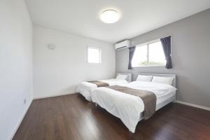 瀬底にあるvilla PILINAの白いベッドルーム(窓付)のベッド2台