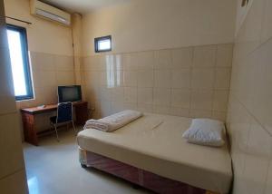 Dormitorio con cama, escritorio y TV en Hotel Mulia Kendari Mitra RedDoorz en Pipulu