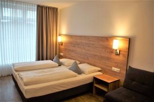 una camera d'albergo con due letti e una sedia di Maiers Hotel Parsberg a Parsberg
