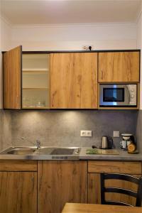 eine Küche mit Holzschränken, einer Spüle und einer Mikrowelle in der Unterkunft Maiers Hotel Parsberg in Parsberg