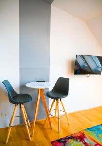 Backpacker Apartment Schönbrunn في فيينا: كرسيين وطاولة في غرفة مع تلفزيون