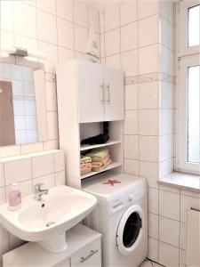 a white bathroom with a washing machine and a sink at Citywohnung am Rannischen Platz I in Halle an der Saale
