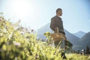 Un uomo in piedi in un campo con un cesto di Tirolerhof a San Leonardo in Passiria
