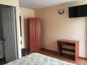 Un dormitorio con una cama, un escritorio y un armario. en Hostal Playa Brava, en Caldera