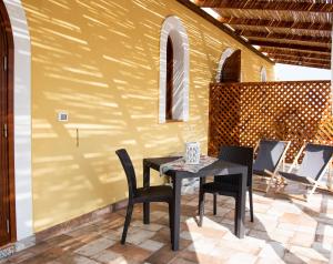 einen Tisch und Stühle auf einer Terrasse mit gelber Wand in der Unterkunft CASE VACANZE I QUATTROVENTI in Lampedusa