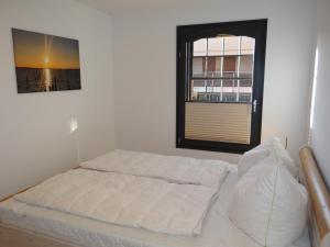 biała sypialnia z łóżkiem i oknem w obiekcie Speicher Residenz Barth E1 App 9 w mieście Barth