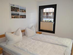 ein weißes Bett mit weißen Kissen und einem Fenster in der Unterkunft Speicher Residenz Barth E1 App 9 in Barth