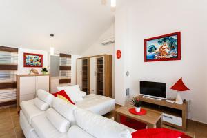 a living room with a white couch and a tv at Apartment Adria 3 in Malinska