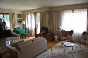 een woonkamer met een bank en stoelen en een televisie bij CRANS MONTANA LE REGENT APPARTEMENT in Crans-Montana