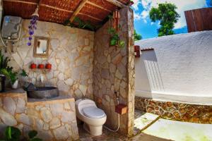 a stone bathroom with a toilet and a bath tub at Ayu Hotel Karimunjawa in Karimunjawa