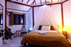 a bedroom with a bed with a mosquito net at Ayu Hotel Karimunjawa in Karimunjawa