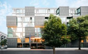ein hohes Gebäude mit einem Baum davor in der Unterkunft KPM Hotel & Residences in Berlin