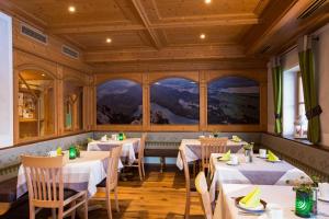 a restaurant with white tables and chairs and windows at Der Helmerhof Allgäu Hideaway in Schwangau