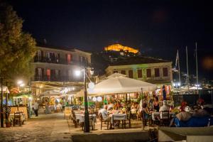 Un groupe de personnes assises à des tables dans une rue la nuit dans l'établissement Sea Horse, à Mithimna