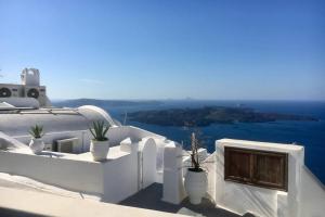 a balcony with potted plants and a view of the ocean at Stefani Cave House Santorini in Firostefani
