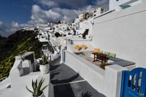 a view of a white building with chairs and plants at Stefani Cave House Santorini in Firostefani