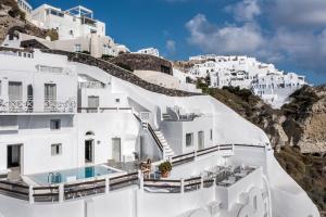 a large white building with a mountain range at Caldera Premium Villas in Oia
