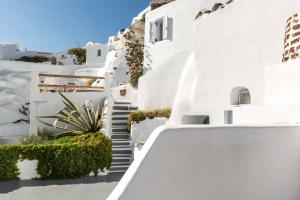 una escalera que conduce a un edificio blanco con plantas en Caldera Premium Villas, en Oia