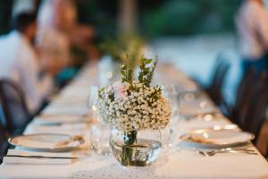 una mesa larga con un jarrón de flores. en Villa Anastasia, en Cugnana