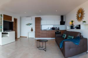 a living room with a brown couch and a kitchen at Vistazur Luxueux appartement avec terrasse et piscine in Rayol-Canadel-sur-Mer