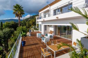 a deck with chairs and tables on a house at Vistazur Luxueux appartement avec terrasse et piscine in Rayol-Canadel-sur-Mer