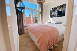 een slaapkamer met een bed en een groot raam bij Luxurious historical Loft close to the beach!! in Wassenaar