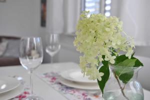 a vase with white flowers on a table with glasses at Ferienwohnung Finja in Bad Dürrheim