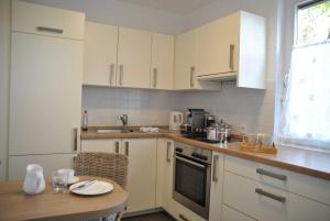 a kitchen with white cabinets and a table and a sink at Ferienwohnung Finja in Bad Dürrheim