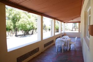 porche con mesa, sillas y ventanas en Mieliefontein Karoo Guest Farm, en Hanover Road