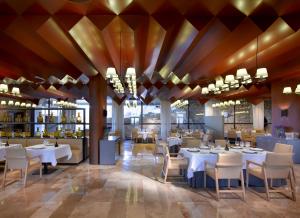 un restaurante con mesas y sillas blancas y un bar en Parador de Lorca, en Lorca