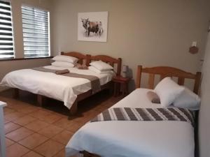 a room with three beds in a room at Acorn Lodge & SKYDECK in Potchefstroom