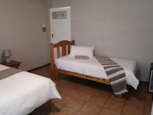 a bedroom with two beds with white sheets at Acorn Lodge & SKYDECK in Potchefstroom