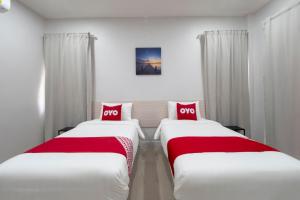 2 camas en una habitación de hotel con almohadas rojas en Capital O 75378 Thawapee Resort en Rayong