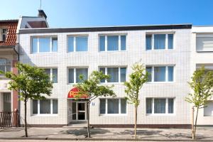 un immeuble d'appartements avec des arbres devant lui dans l'établissement Ferienhaus Papenfuß, à Norderney