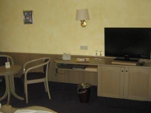 a room with a desk with a television and a table with a chair at Hotel-Gasthof Rangau in Ansbach