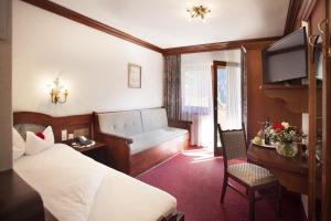 um quarto de hotel com uma cama, uma secretária e uma televisão em Hotel Almhof em Neustift im Stubaital