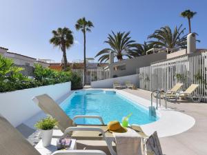 einen Pool mit Stühlen und einem Tisch neben einem Haus in der Unterkunft VelSuites Playa del Ingles by VillaGranCanaria in Playa del Ingles