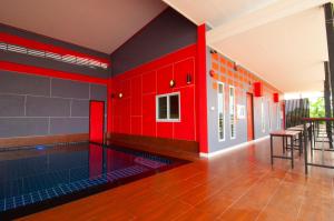 uma piscina no meio de uma sala com paredes vermelhas em The Palm Resort Kampeang Saen em Nakhon Pathom