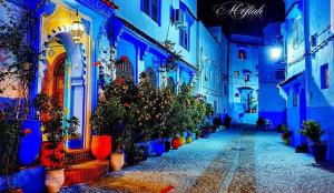 un callejón con macetas y edificios por la noche en Dar Yakout, en Chefchaouen