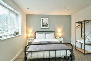 a bedroom with a bed with two lamps and a window at School Path Ironbridge Townhouse with Roof Terrace in Ironbridge