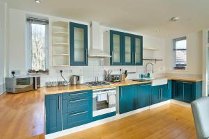 a large kitchen with blue cabinets and wooden floors at School Path Ironbridge Townhouse with Roof Terrace in Ironbridge