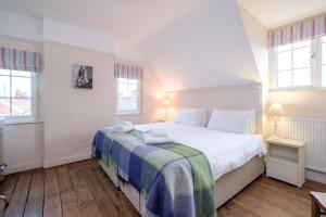 Un dormitorio con una cama blanca con una manta azul y verde. en Sanctuary House, en Thorpeness