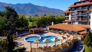a hotel with a swimming pool with chairs and umbrellas at The Balkan Jewel Resort, Trademark Collection by Wyndham in Bansko