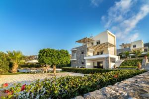 un gran edificio blanco con un jardín delante de él en Aroma Villas, en Hersonissos